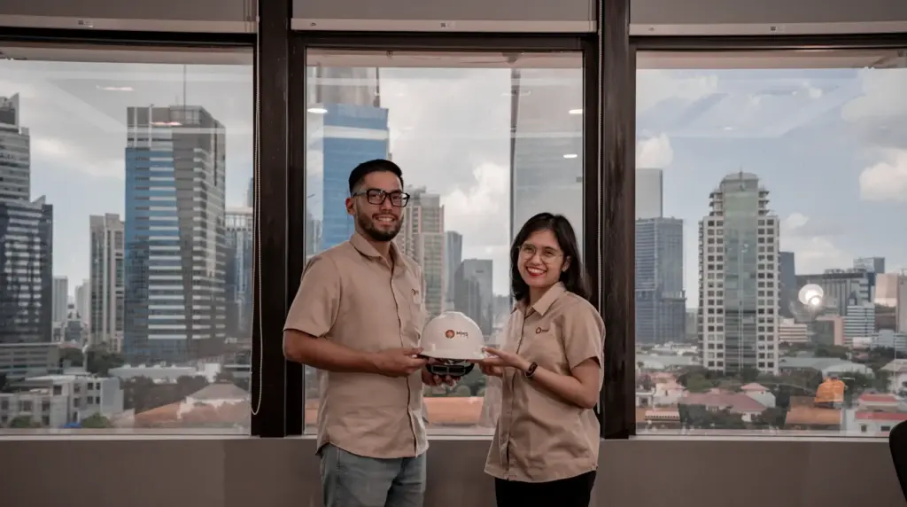 Two engineers in hard hats reviewing security and ELV plans in a Doha high-rise