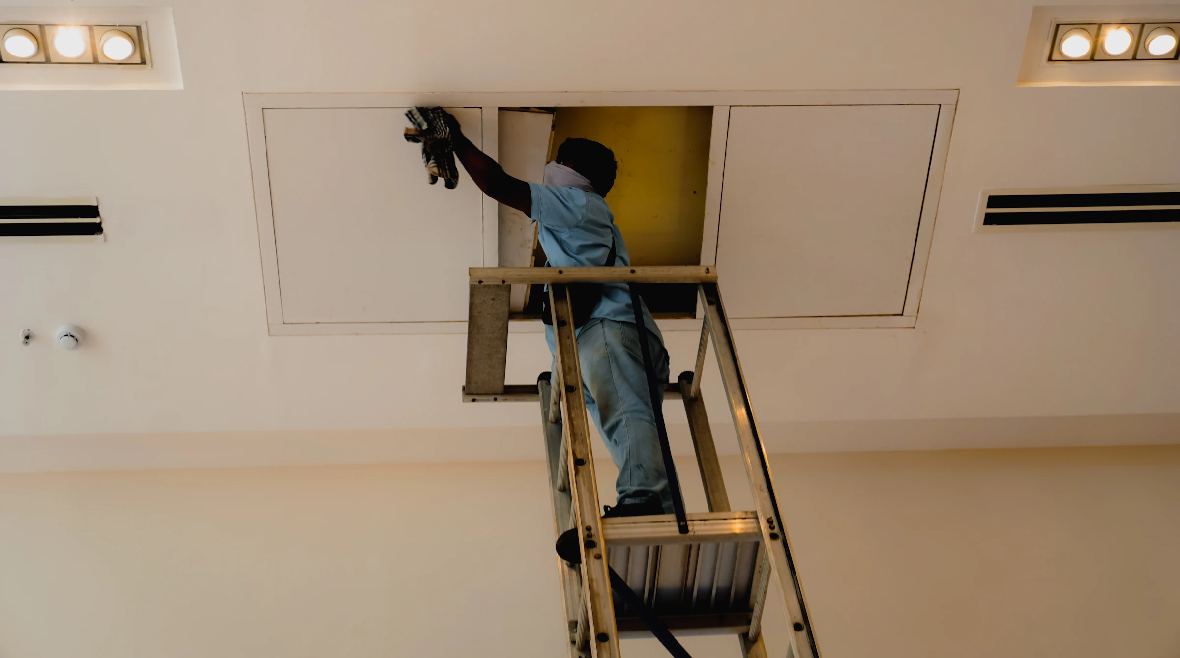 Technician on a ladder installing ceiling equipment